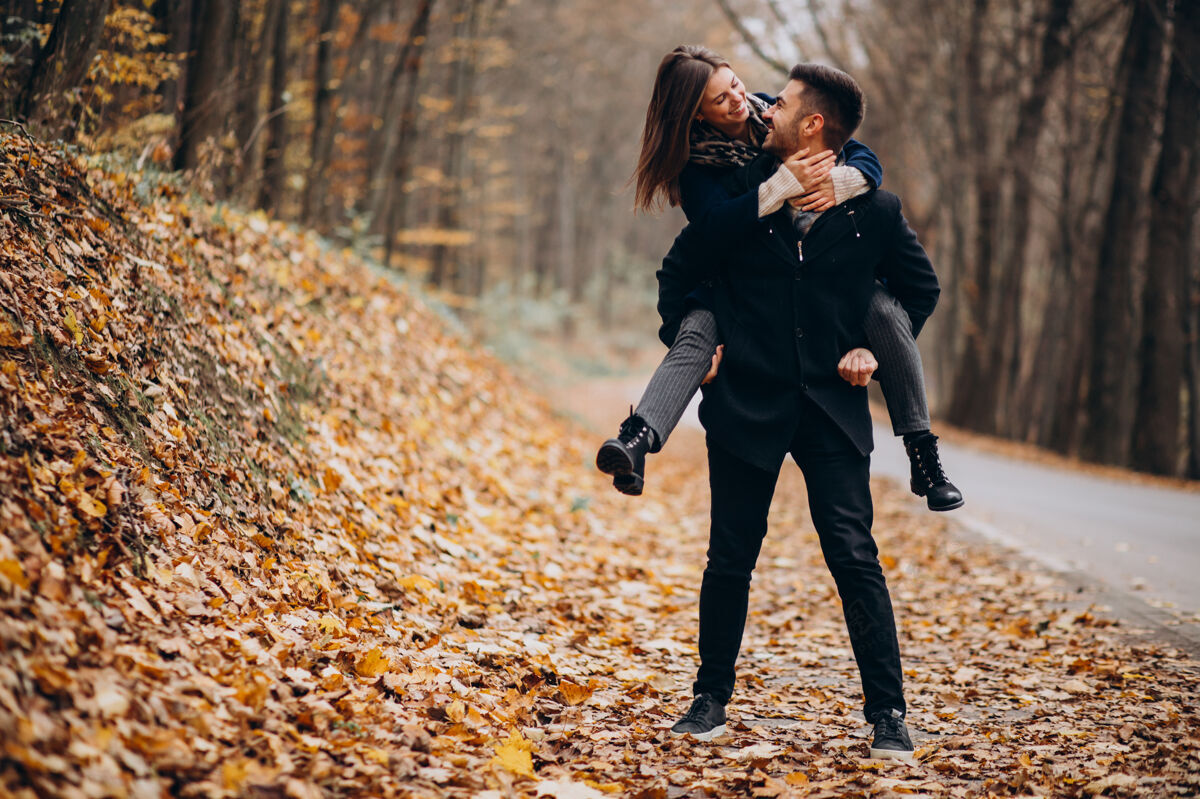 男人一对年轻夫妇在秋天的公园里散步快乐的女人女人浪漫