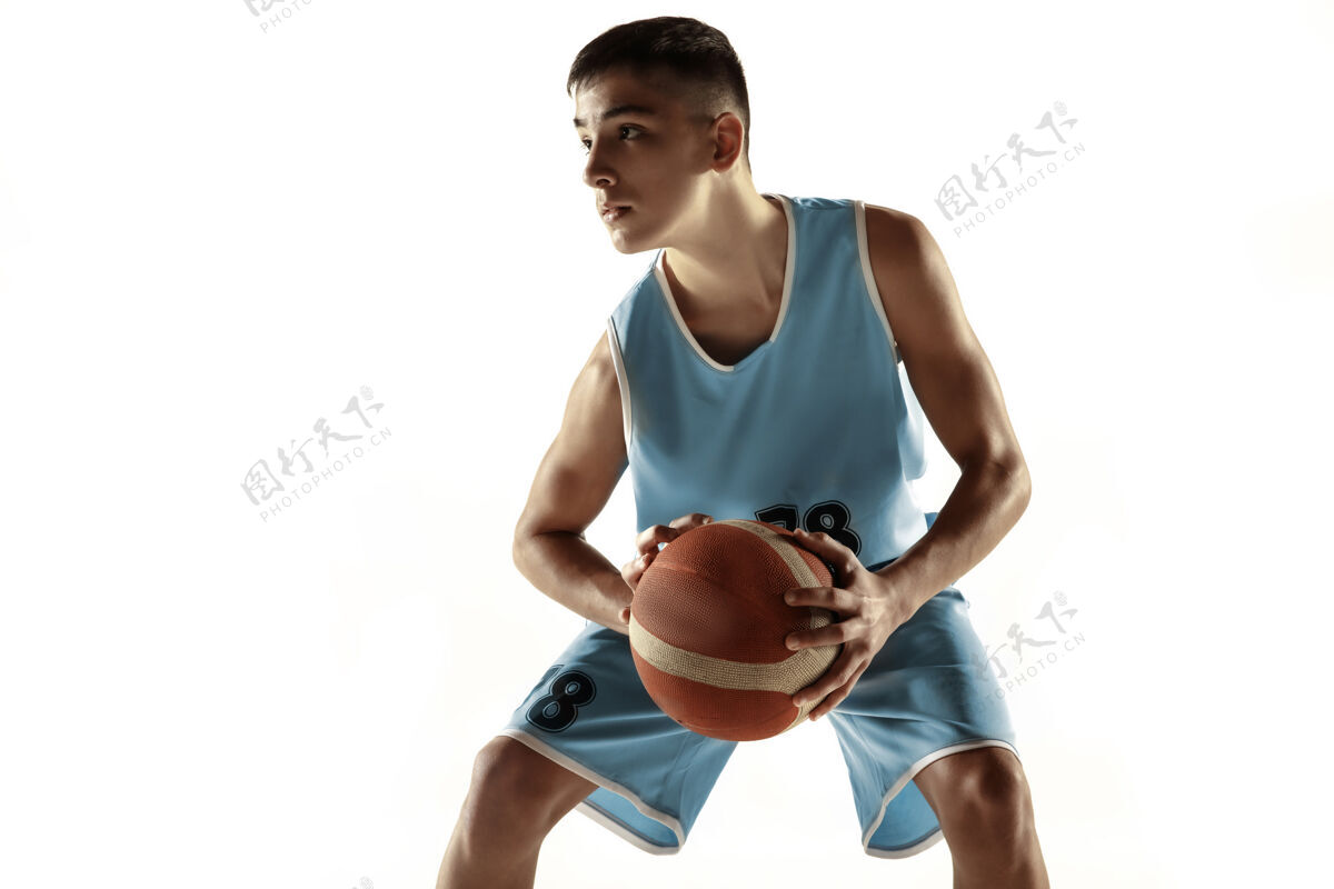 跳跃在白色工作室背景上 年轻篮球运动员拿着一个孤立的球的全长肖像青少年训练和练习 动作运动的概念 动作 健康的生活方式 广告运动员青少年篮球