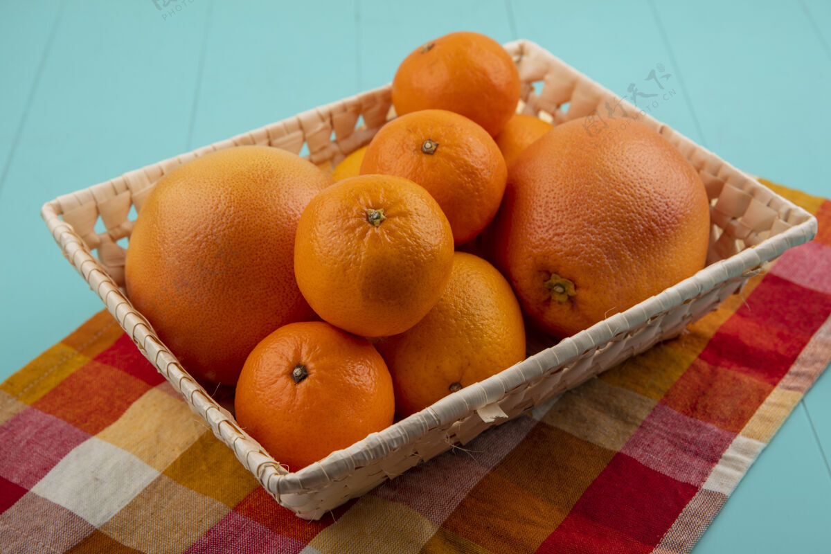 绿松石侧视图橘子和葡萄柚在一个篮子里在一个格子毛巾上的绿松石背景风景葡萄柚毛巾