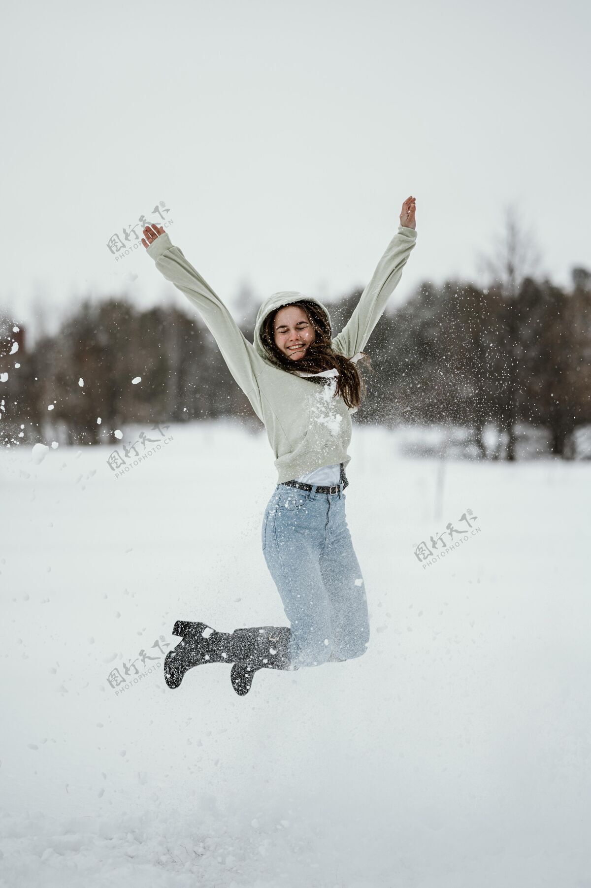 姿势快乐的女人在冬天跳到户外市民自然欢呼