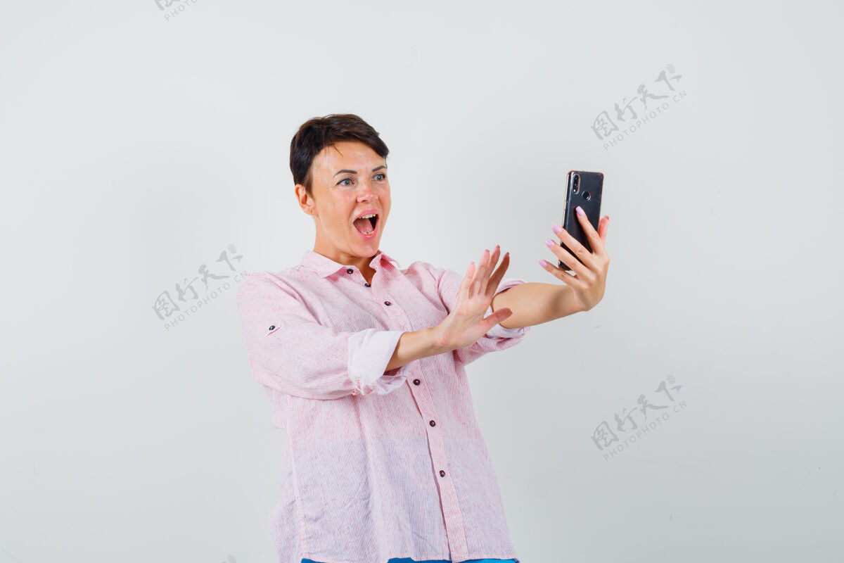 成人穿着粉色衬衫的女性正在视频聊天 看起来很兴奋 正对着镜头聊天肖像爆发