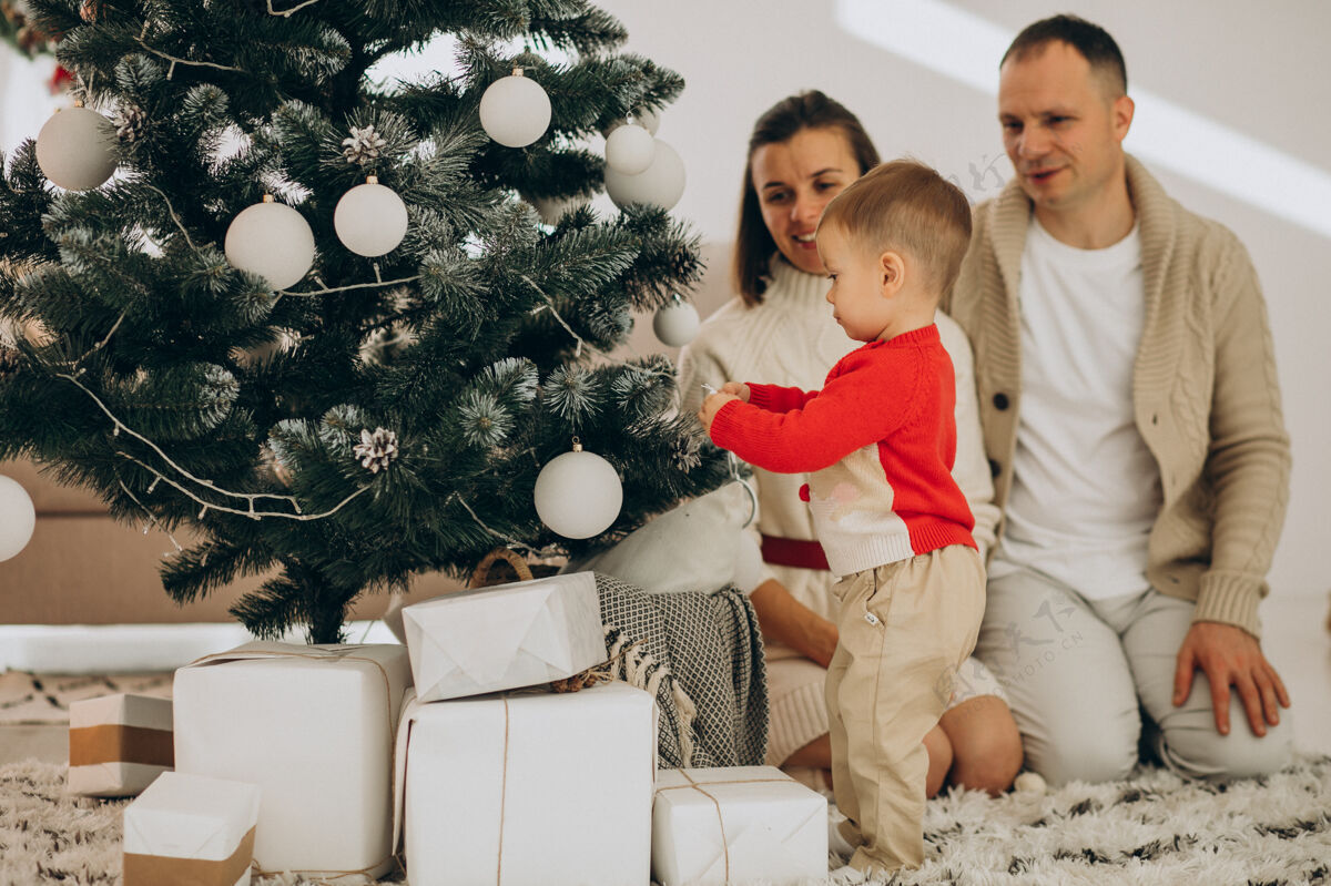 儿子一家人带着小儿子在家里的圣诞树旁过圣诞节灯现代庆祝