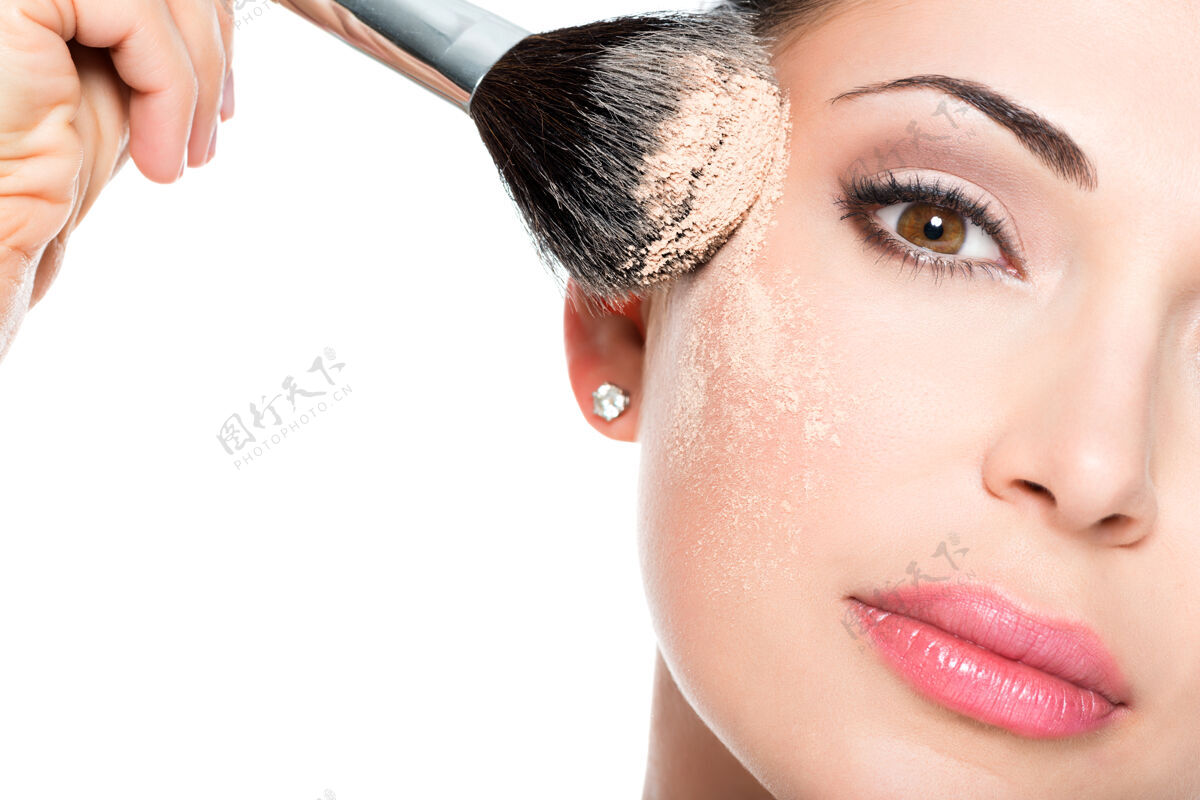 女人一个女人用化妆刷在脸上涂上干妆色调的特写镜头女人 刷子 化妆 化妆品 肖像 魅力 粉 制造 治疗 涂抹 腮红 面容 脸颊 应用