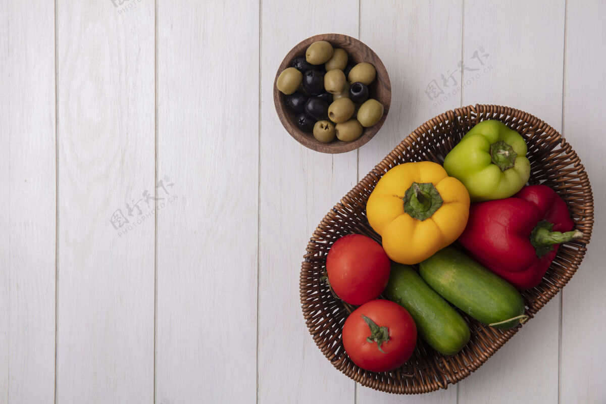 顶部顶视图复制空间甜椒与西红柿黄瓜在一个篮子与橄榄在一个白色的背景铃铛蔬菜胡椒