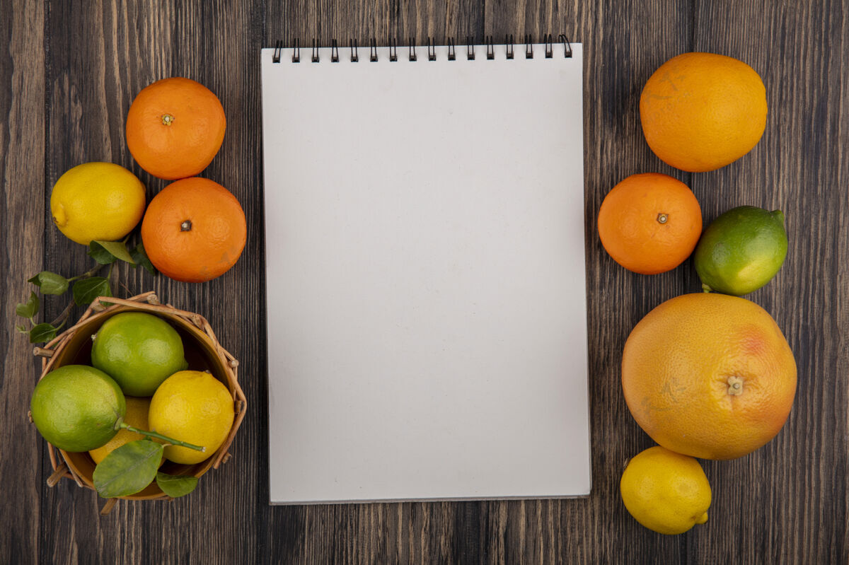 空间顶视图复制空间记事本与葡萄柚 橙子 柠檬和柠檬在一个木制的背景篮子橘子酸橙葡萄柚