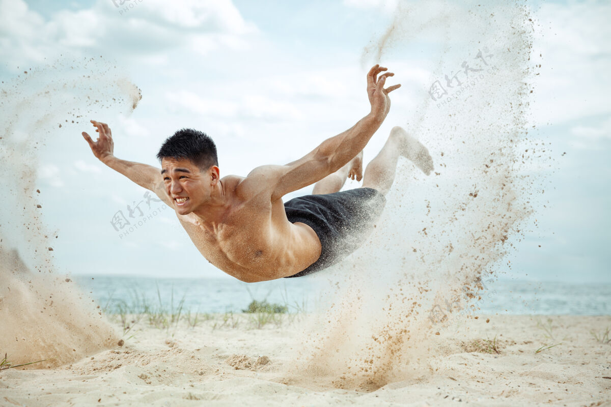 手臂年轻健康的男子运动员在海滩上做深蹲成人交叉人