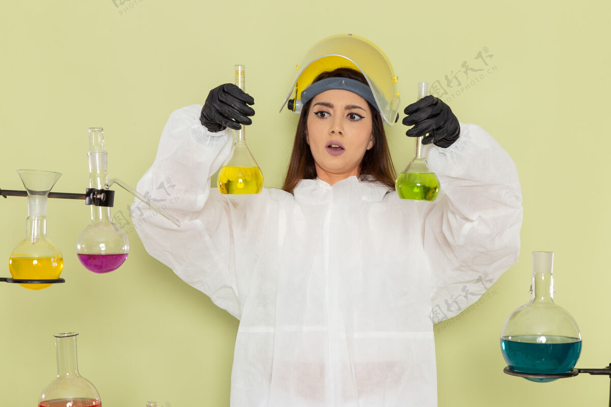 办公桌正面图身着特殊防护服的女化学家在绿色办公桌上处理溶液实验室解决方案工作