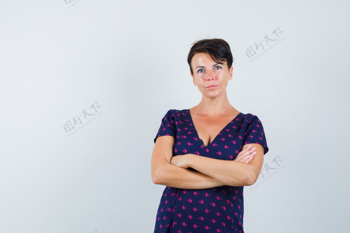 成人黑发女子交叉双臂站在紫色和红色图案的裙子 看起来很高兴前视图微笑化妆休闲