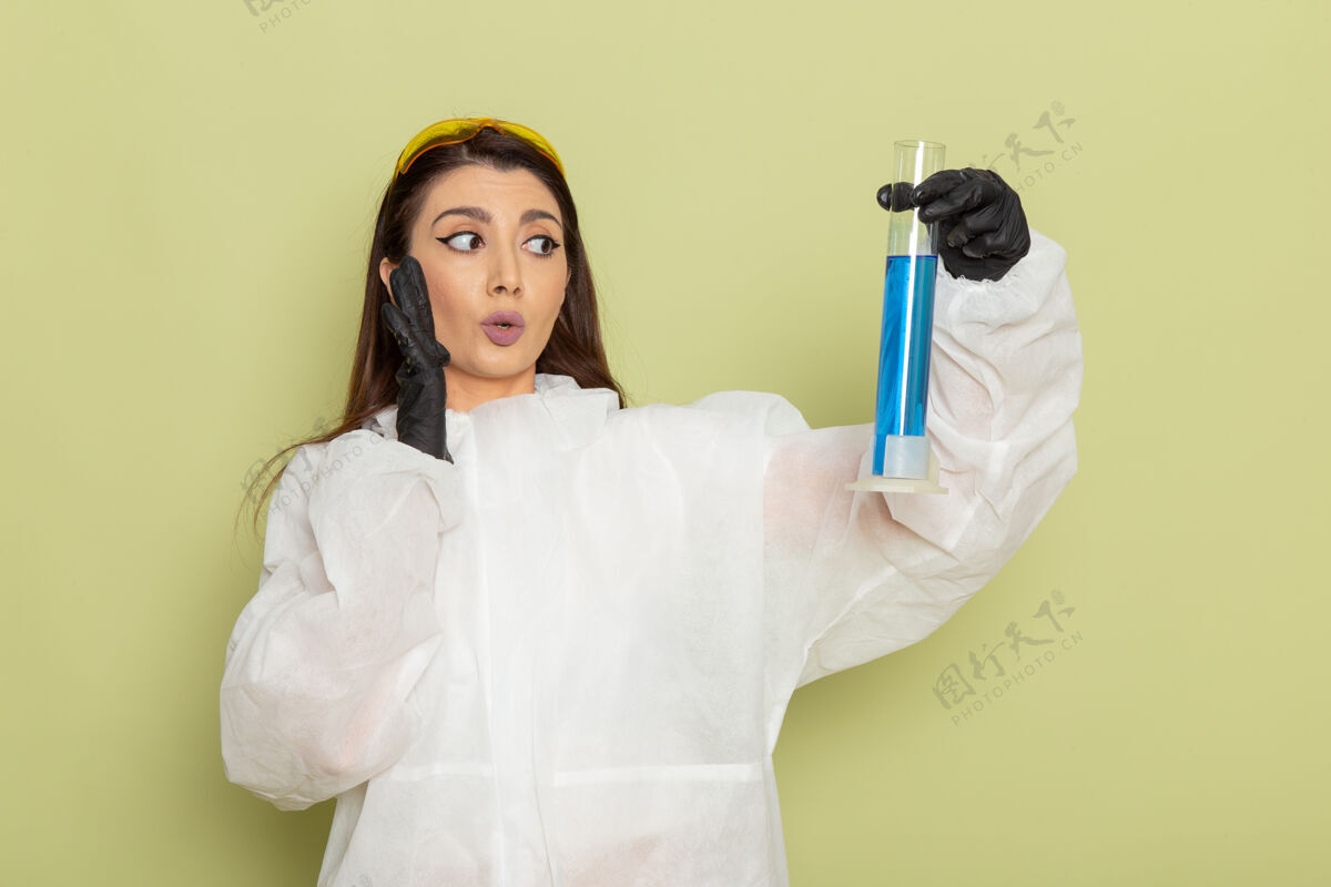科学正面图穿着特殊防护服的女化学家拿着浅绿色表面上有溶液的烧瓶正面护士工作