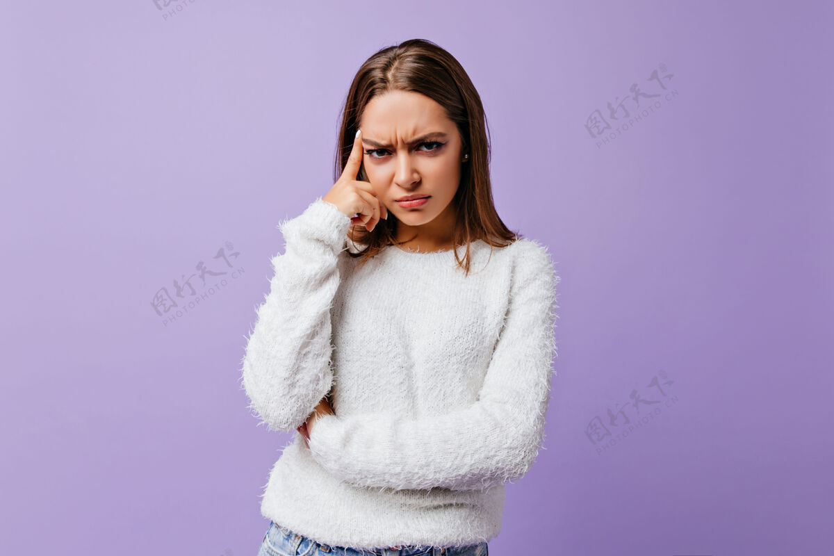 肖像情绪激动的黑发女人带着愤怒和愤慨在丁香花上为女性画像摆姿势不开心的穿着羊毛衫的女孩抚摸着她的脸现代模特快乐