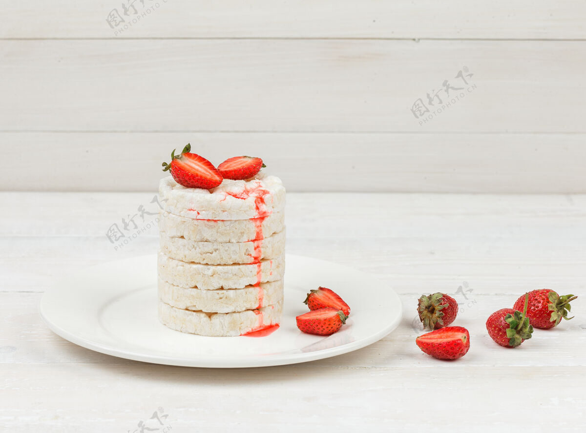 早餐高角度观看白米饼与草莓在白色木板表面板米糕甜点板