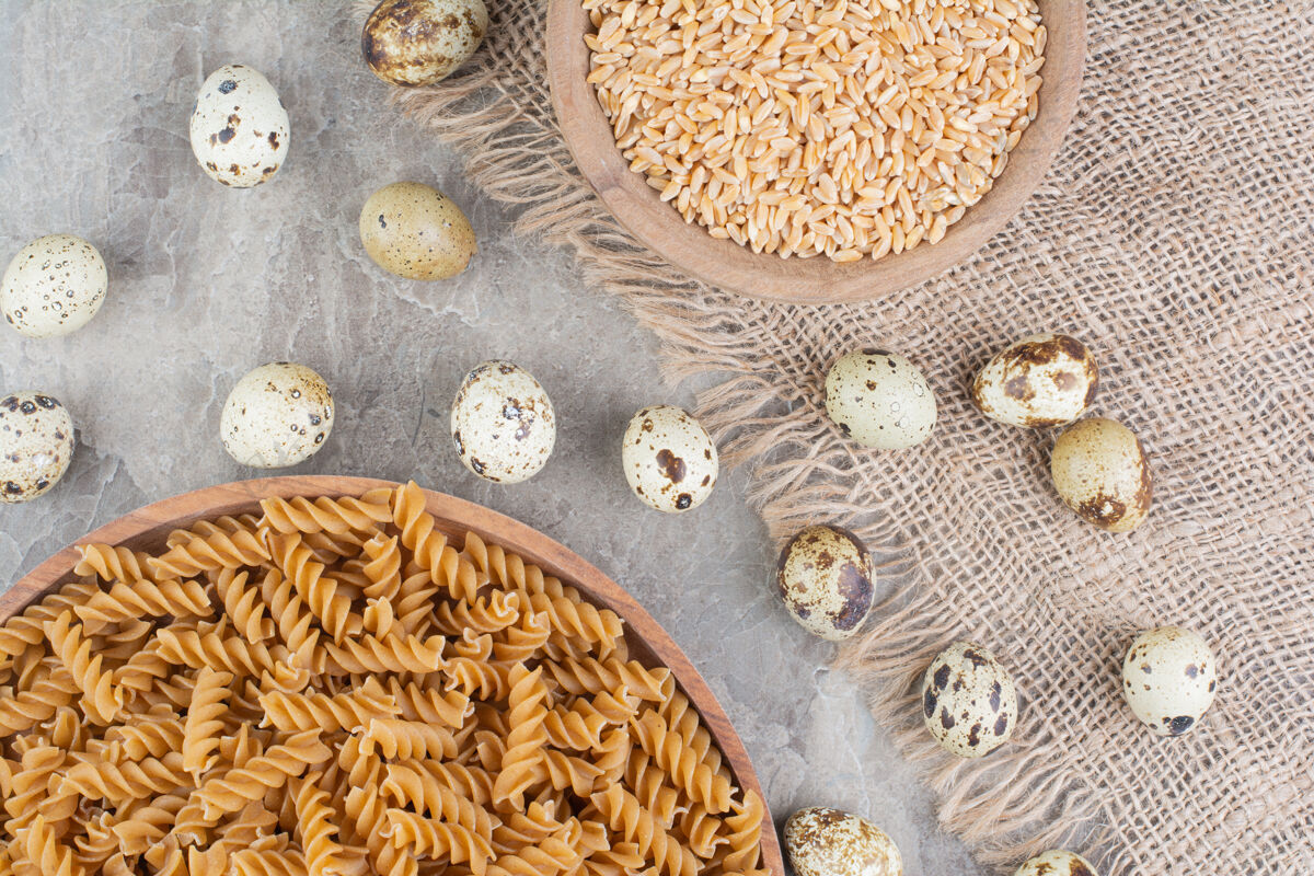 生物把意大利面放在一个木盘里 上面放着小麦粒和鹌鹑蛋餐厅厨房产品