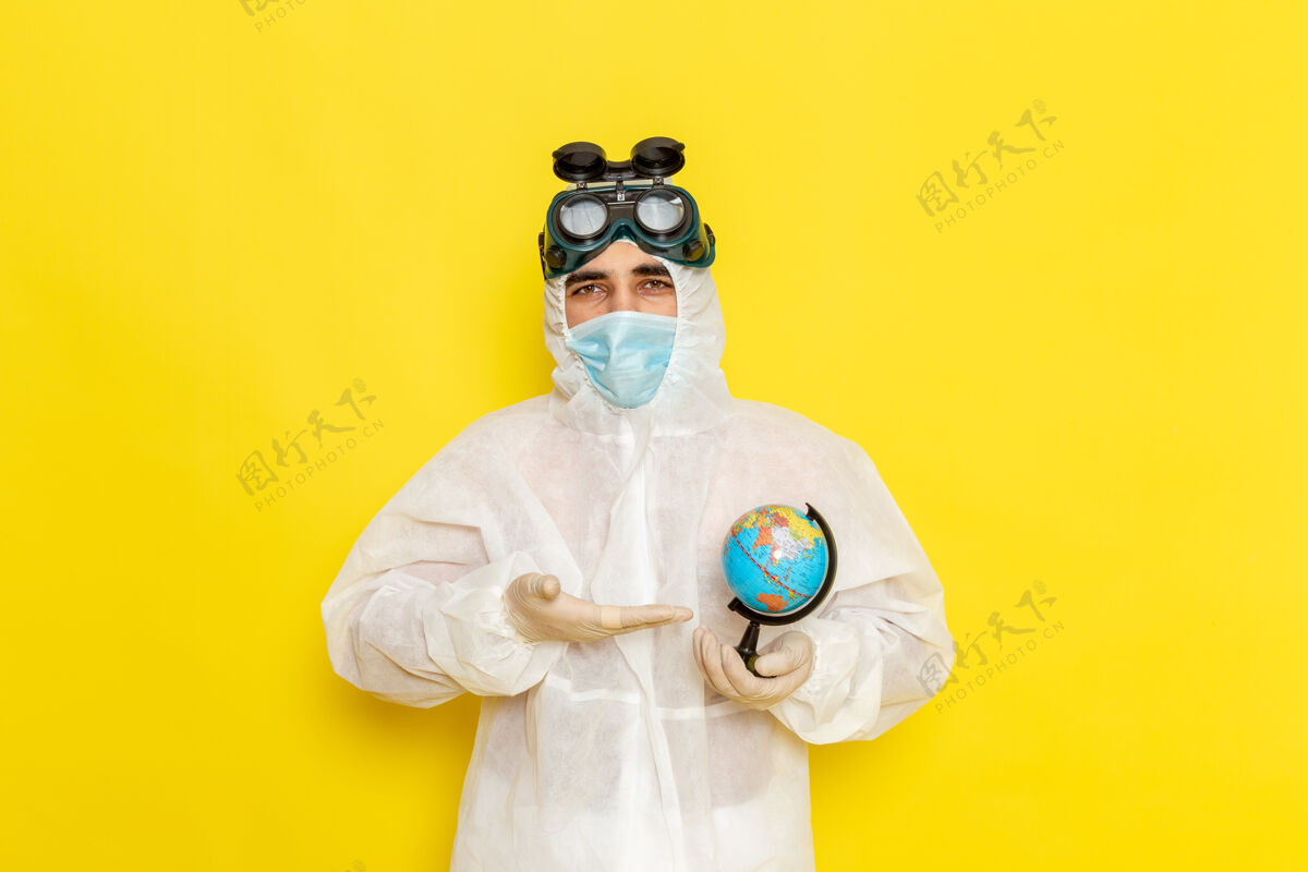 特殊正面图：黄色办公桌上 一位身着特殊套装的男科学工作者手里拿着一个小圆球前面西装圆