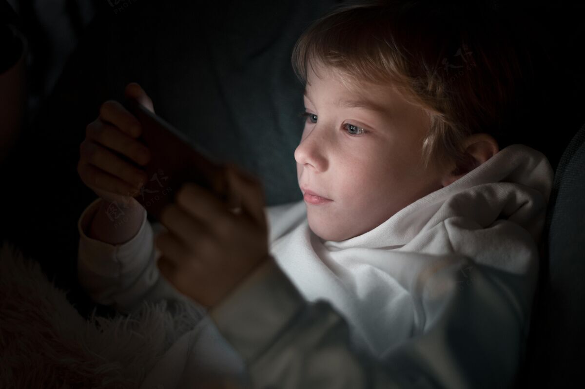 移动小男孩晚上在床上用智能手机电子科技青年