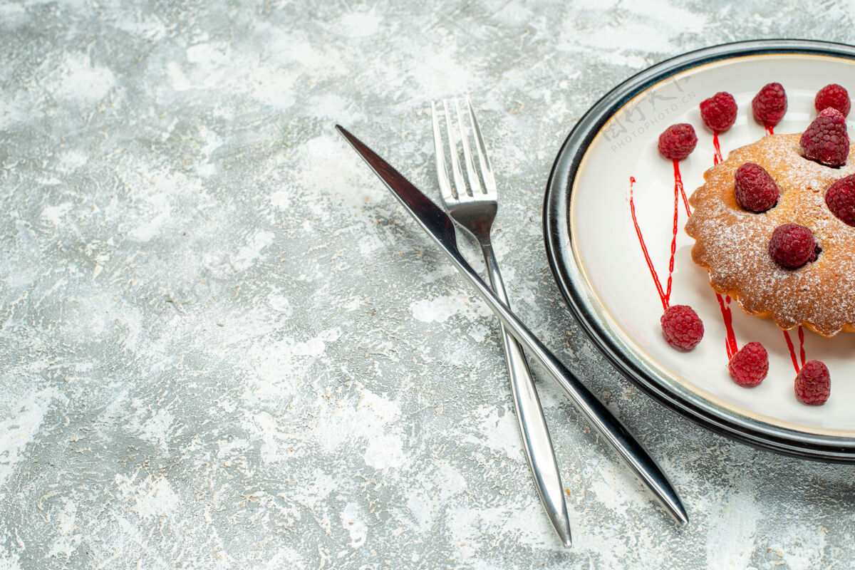 钢笔俯瞰浆果蛋糕在白色椭圆形盘子交叉叉和餐刀在灰色表面自由空间椭圆公开信盘子