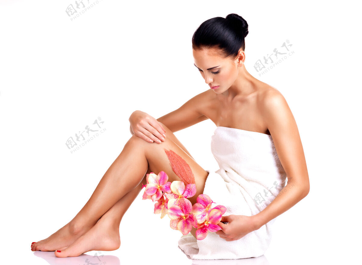 治疗美丽的年轻女子用花草擦洗裸体坐着化妆品