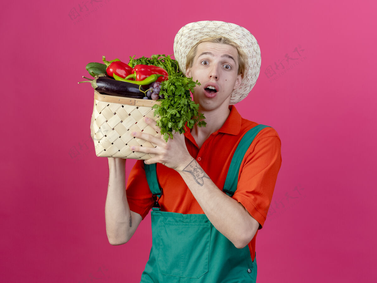 园丁年轻的园丁穿着连体衣戴着帽子拿着装满蔬菜的箱子板条箱帽子蔬菜