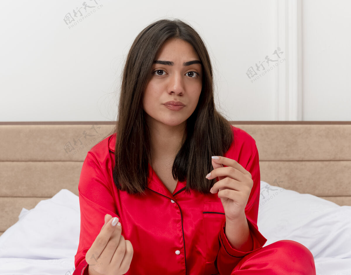女人穿着红色睡衣在床上放松的年轻美女年轻怀疑看着