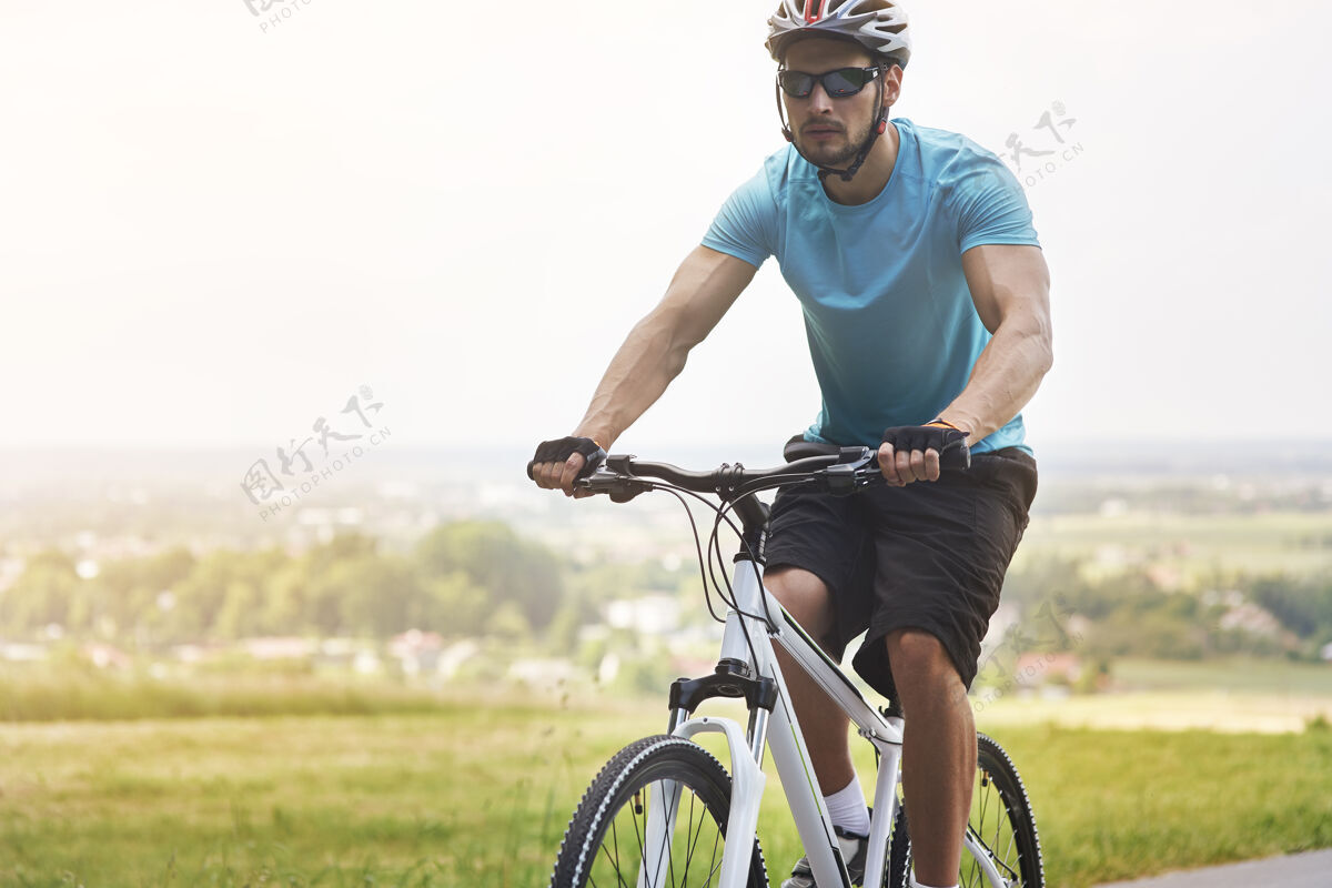 头盔夏天骑自行车的帅哥男子继续运动