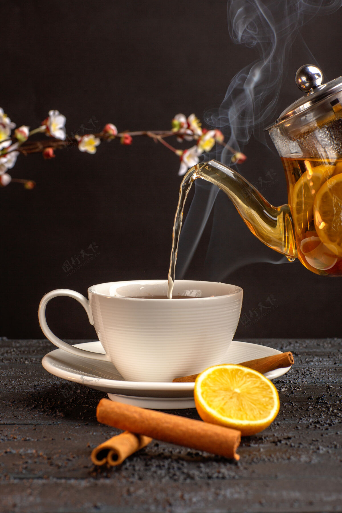混合饮料一杯柠檬肉桂茶和茶壶放在灰色的桌子上咖啡柑橘杯子