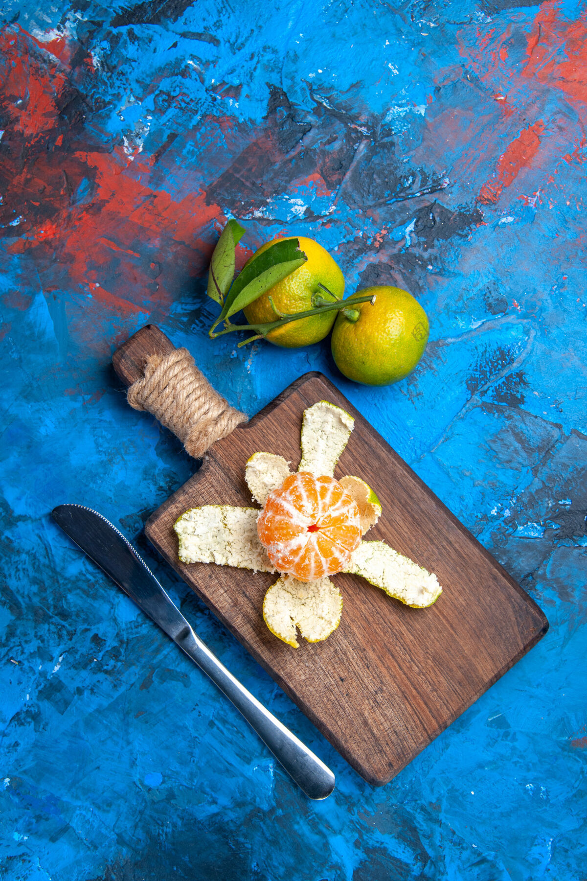 视图俯瞰削皮柑桔上的砧板晚餐刀新鲜柑桔与叶子上的蓝色表面自由的地方地方柑橘柑桔