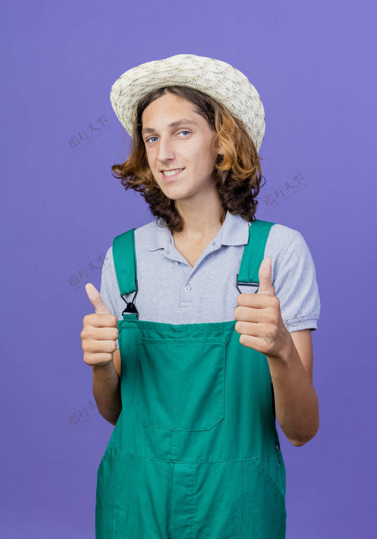 向上年轻的园丁穿着连体衣 戴着帽子 微笑着竖起大拇指男人帽子微笑