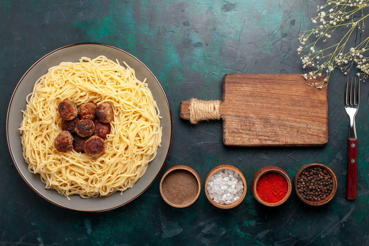 晚餐顶视图煮熟的意大利面食与肉丸和调味品在深蓝色的表面烹饪美味顶部