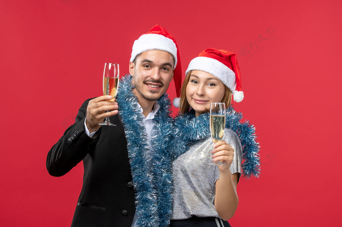 帽子前视图年轻夫妇刚刚庆祝新年红桌爱圣诞派对微笑快乐年轻夫妇