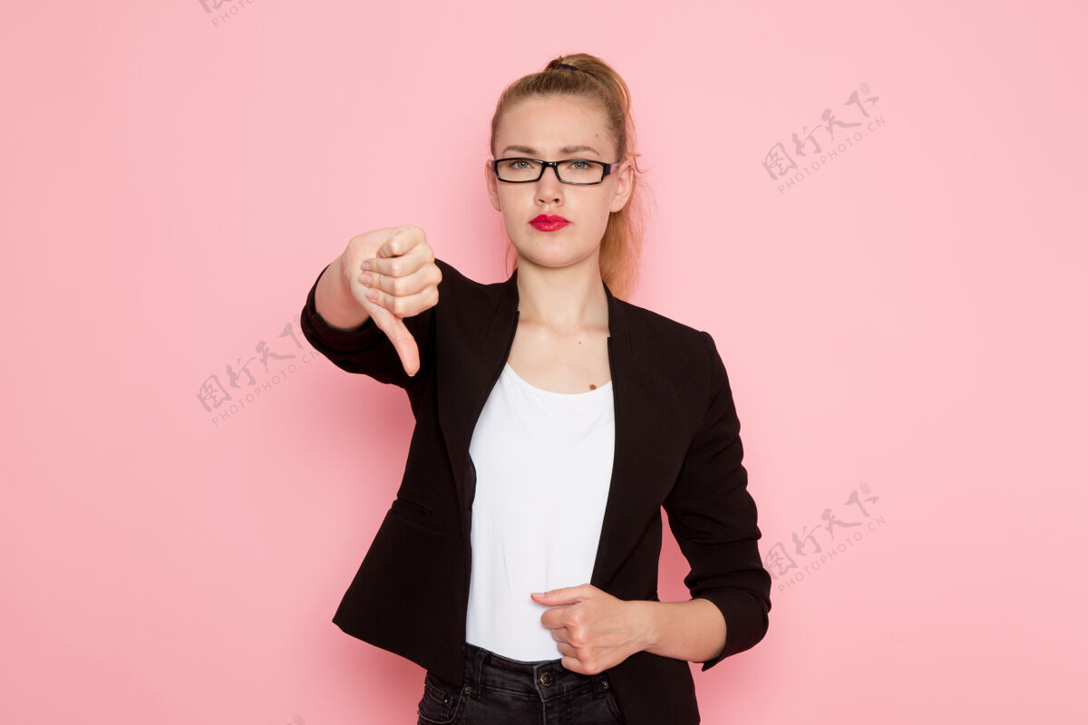 模特穿着黑色紧身夹克的女上班族的正面图 在浅粉色的墙上显示出不同的标志女上班族脸显示