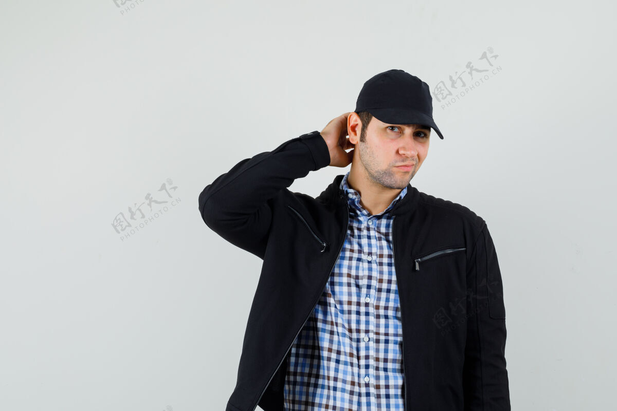 同时穿着衬衫 夹克 帽子的年轻人一边搔头一边摆姿势 看起来很优雅现代胡须衬衫
