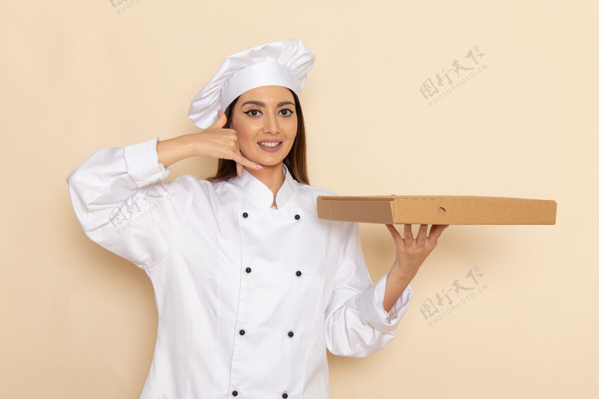 举行身穿白色厨师服的年轻女厨师正拿着食物盒站在浅白的墙上工人工作工作
