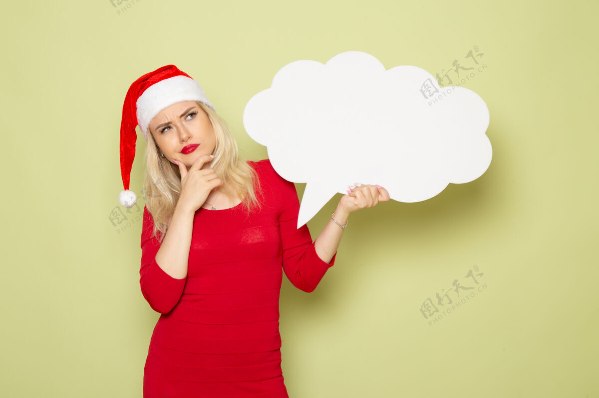 肖像正面图美丽的女性手持云状白色标志在绿色墙上圣诞雪照片假日新年美丽的女人云帽子