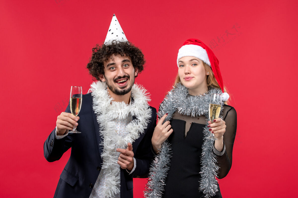 风景正面图：年轻夫妇在红墙假日圣诞爱情派对上庆祝新年服装成人年轻夫妇
