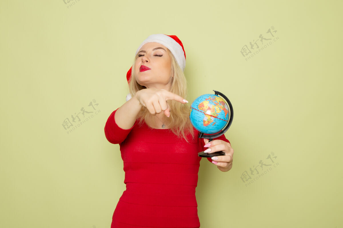 风景前景靓女抱着小地球仪在绿墙上过节感慨圣诞新年雪彩地球成人小