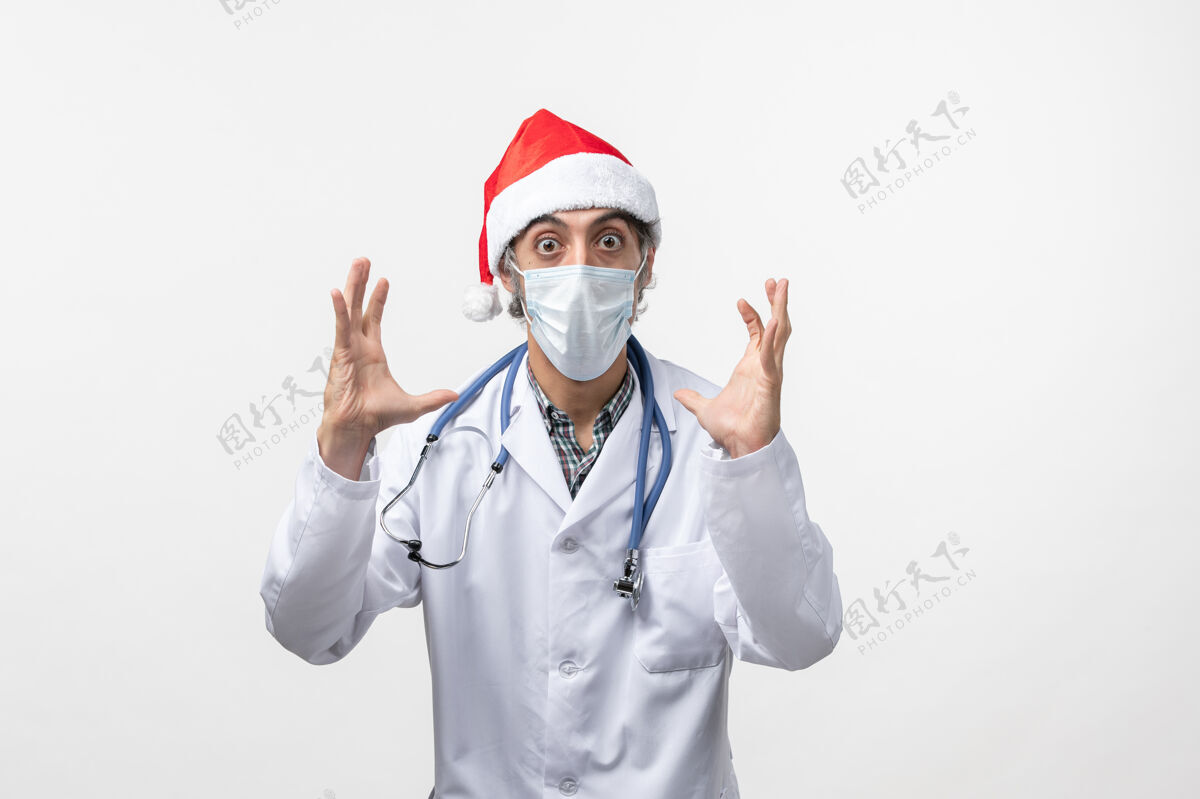 圣诞节正面图白色办公桌上戴着口罩的男医生大流行性冠状病毒假日病毒护士听诊器实验室外套