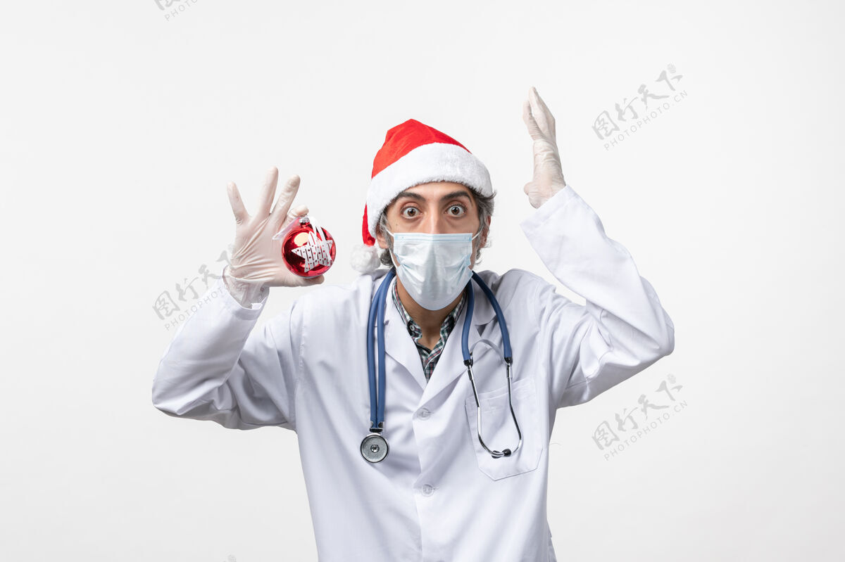 成人正面图白墙上戴着玩具面具的男医生健康共济新年病毒圣诞节病毒冠状病毒