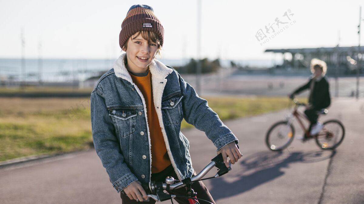 休闲当他的朋友骑自行车时 男孩摆姿势活跃儿童水平