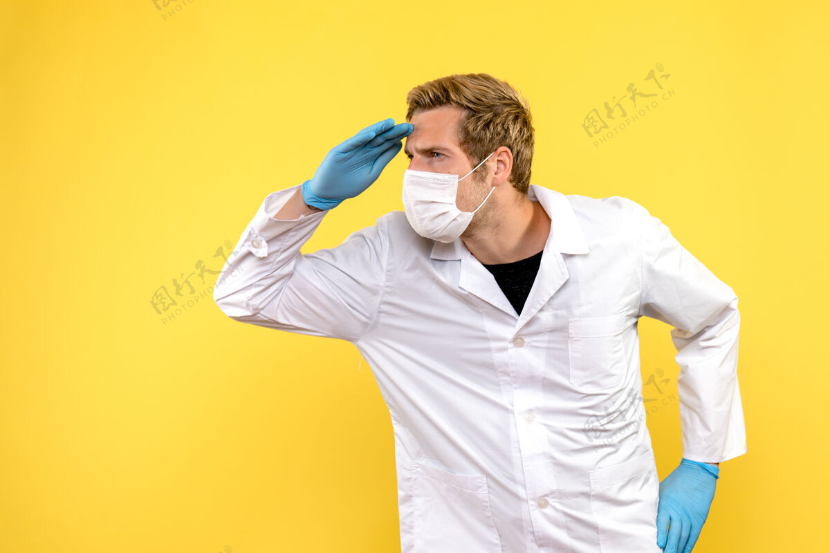 医生正面图黄色背景上的男医生正在看远处的大流行科维德健康医生成人冠状病毒商人