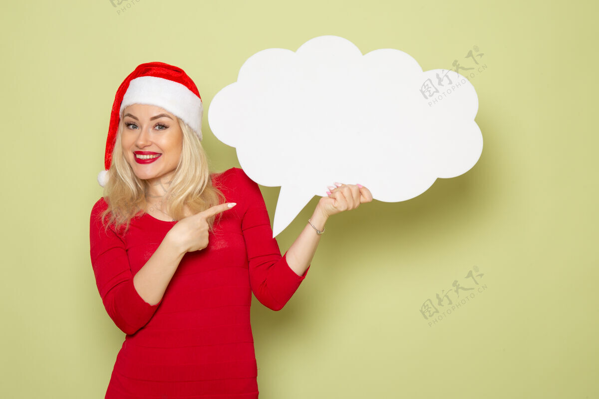 情感正面图美女手持绿色墙上的白色大招牌新年雪景照片圣诞感慨帽子微笑美丽