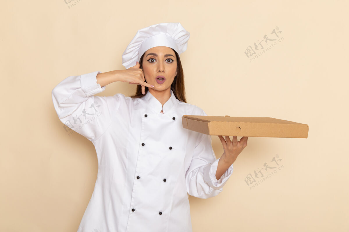 烹饪身穿白色厨师服的年轻女厨师正拿着食物盒站在浅白的墙上护士肖像人