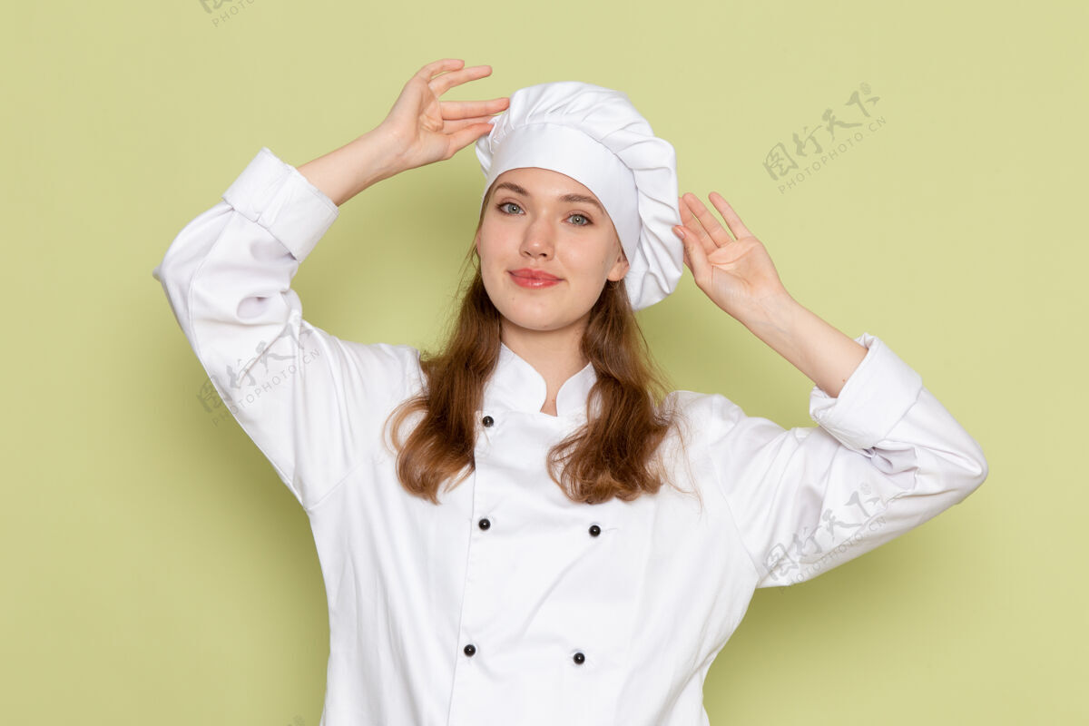 人身着白色厨师服的女厨师在绿色墙壁上微笑的正面视图厨房快乐人