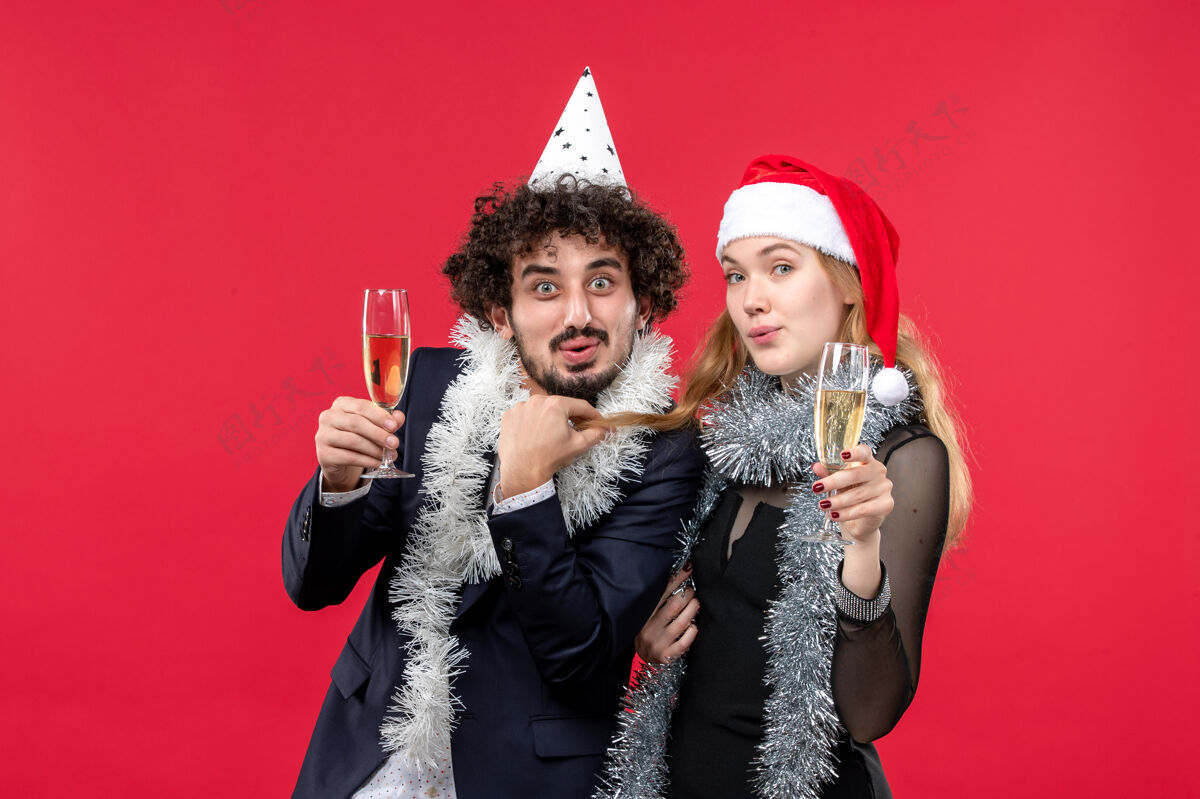 肖像前视图年轻夫妇庆祝新年在红地板假日圣诞爱党服饰微笑服装