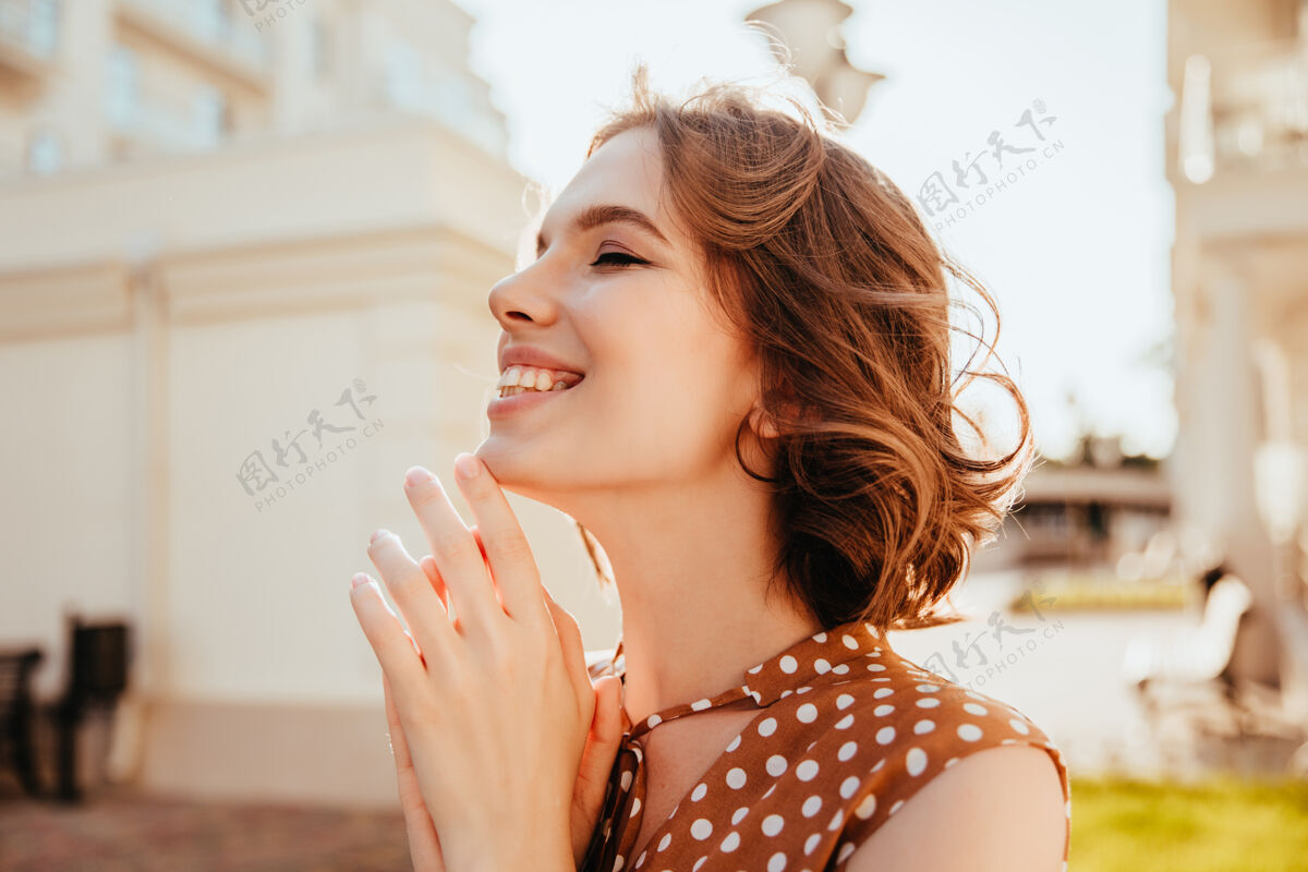 微笑美丽的短发女孩在户外情绪化地摆出姿势漂亮的黑发女模特在街上大笑迷人漂亮城镇