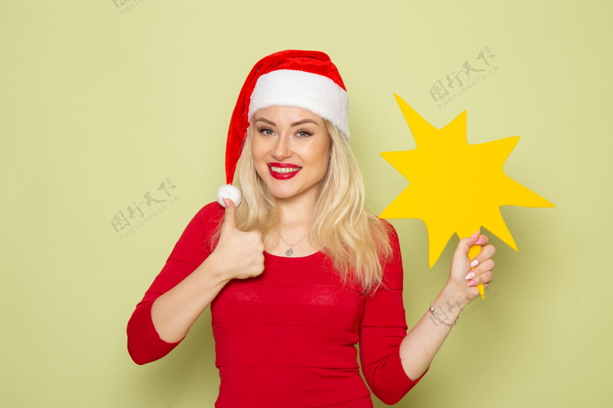 肖像正面图漂亮的女人抱着大黄色的身影在绿色的墙上彩色的节日情感雪新年圣诞节圣诞节漂亮的女人颜色