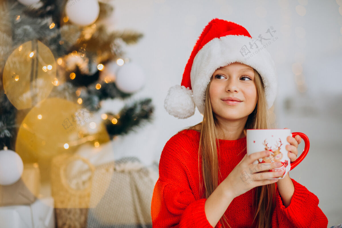 青少年在圣诞树旁喝可可的女孩节日人美丽