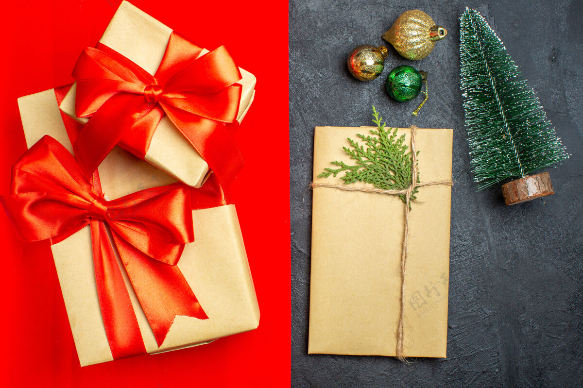 圣诞俯视美丽的礼物与蝴蝶结形丝带旁边的杉树枝装饰配件上的红色背景蝴蝶结顶部配件