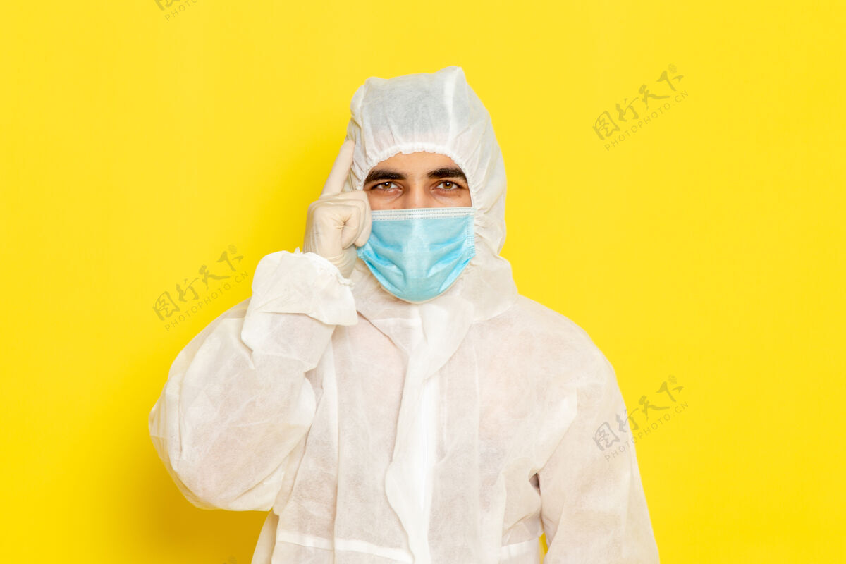 医疗身穿白色特殊防护服 浅黄色墙上带面罩的男性科学工作者的正面图特殊医生男性