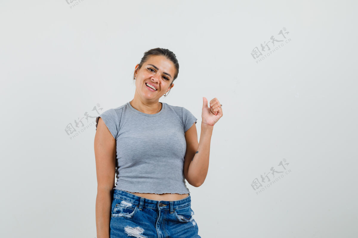 短裤年轻的女性在t恤 短裤上竖起大拇指 看起来很快乐大拇指漂亮黑发