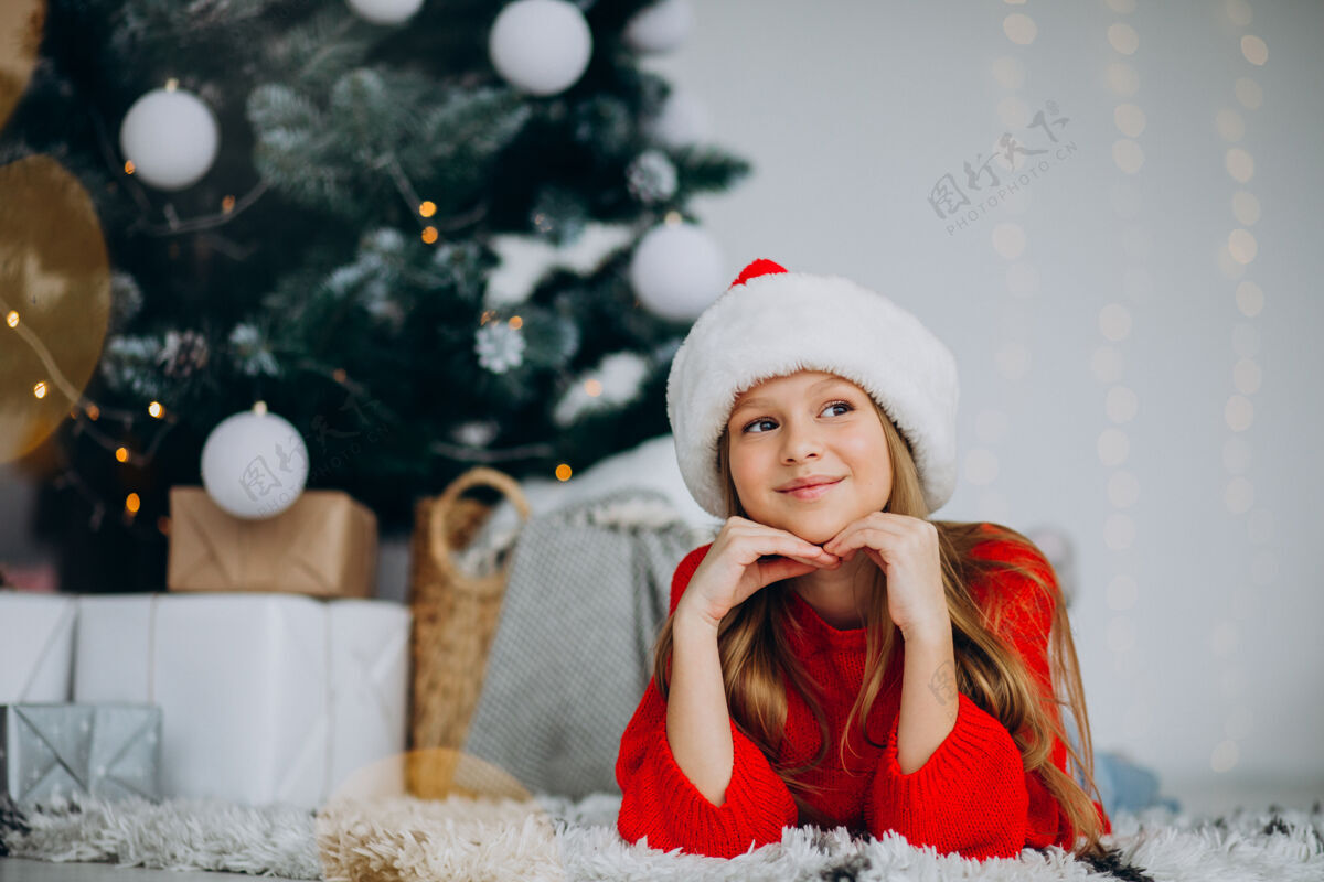 圣诞树圣诞树下戴圣诞帽的漂亮女孩红色毛衣人装饰