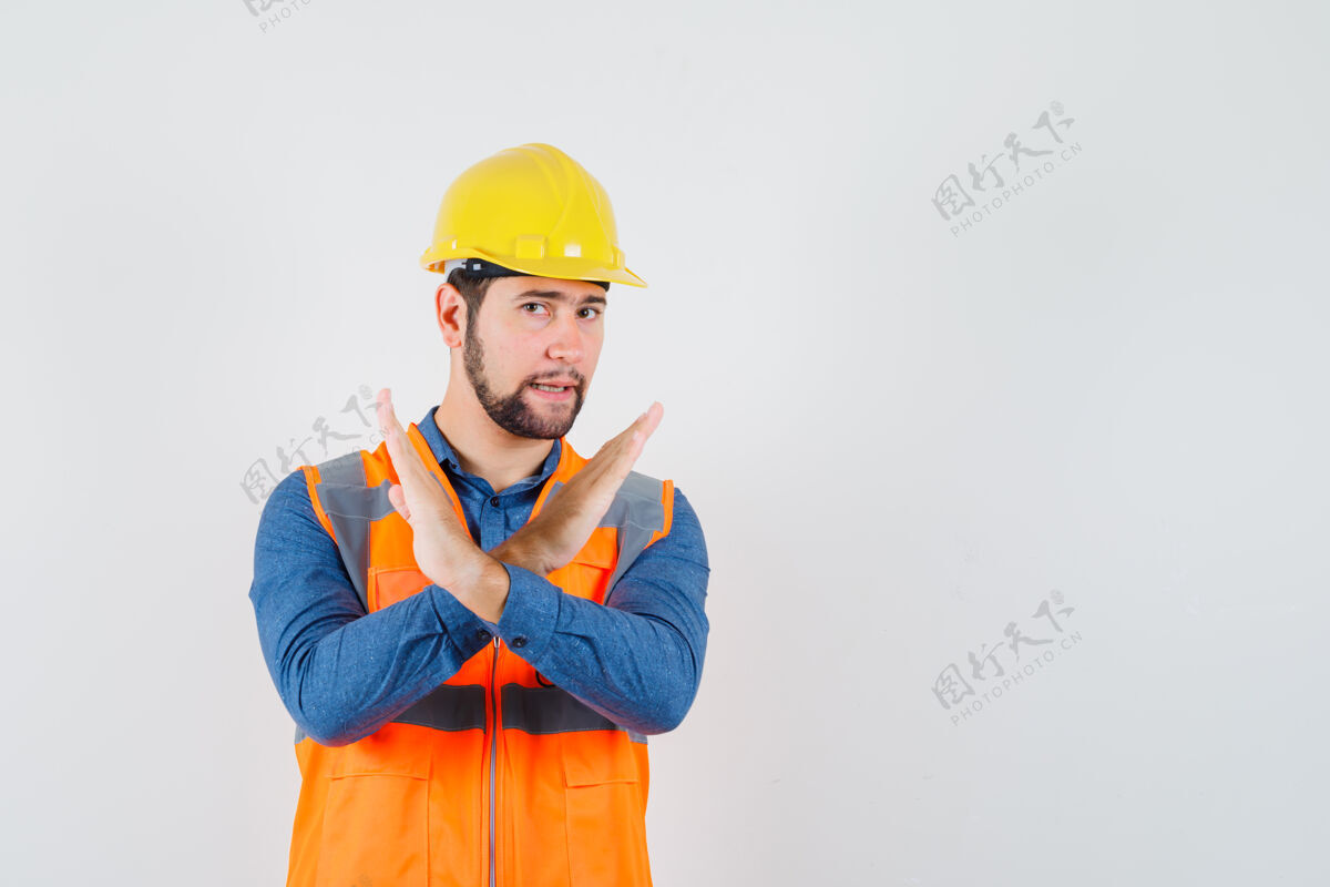 硬年轻的建设者在衬衫 背心 头盔上展示停车姿势 看起来很恼火前视图建筑商建筑工程师